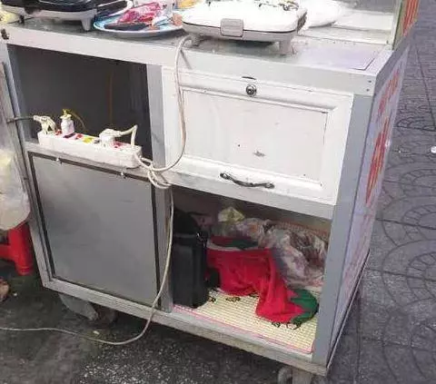 母親忙著賣食物賺生計,忙不過來的時候就會將嬰兒放進小吃車下面的櫃子裡,引網友爭議!