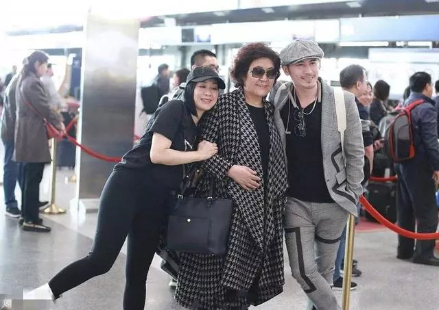 49歲鍾麗緹機場高調秀恩愛,卻被59歲婆婆搶鏡,穿格紋大衣太有范!